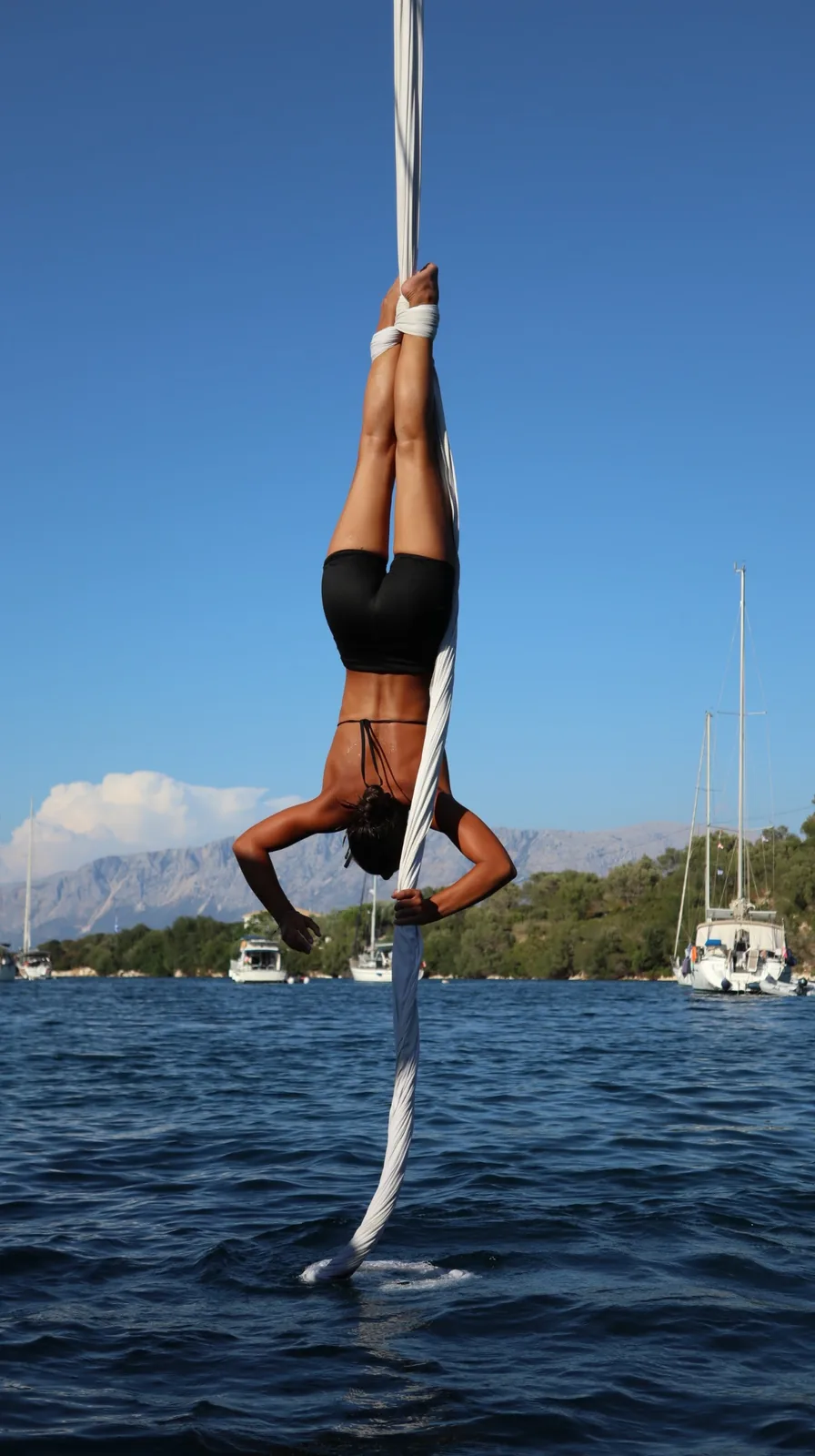 Inverted with feet drawn up on the silk, boats and mountains behind